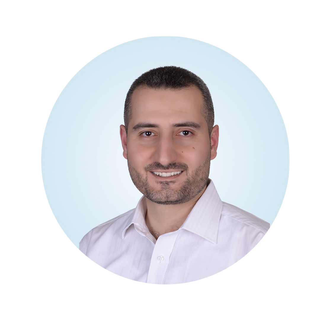 Head-and-shoulders portrait of a smiling man with short dark hair and a trimmed beard, wearing a white collared shirt, against a light blue circular background.